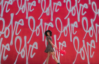 Dressed in brown and black miniskirt woman standing beside the graffiti
